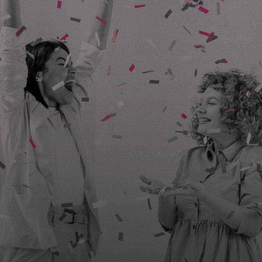 Two women cheering as confetti falls over them.